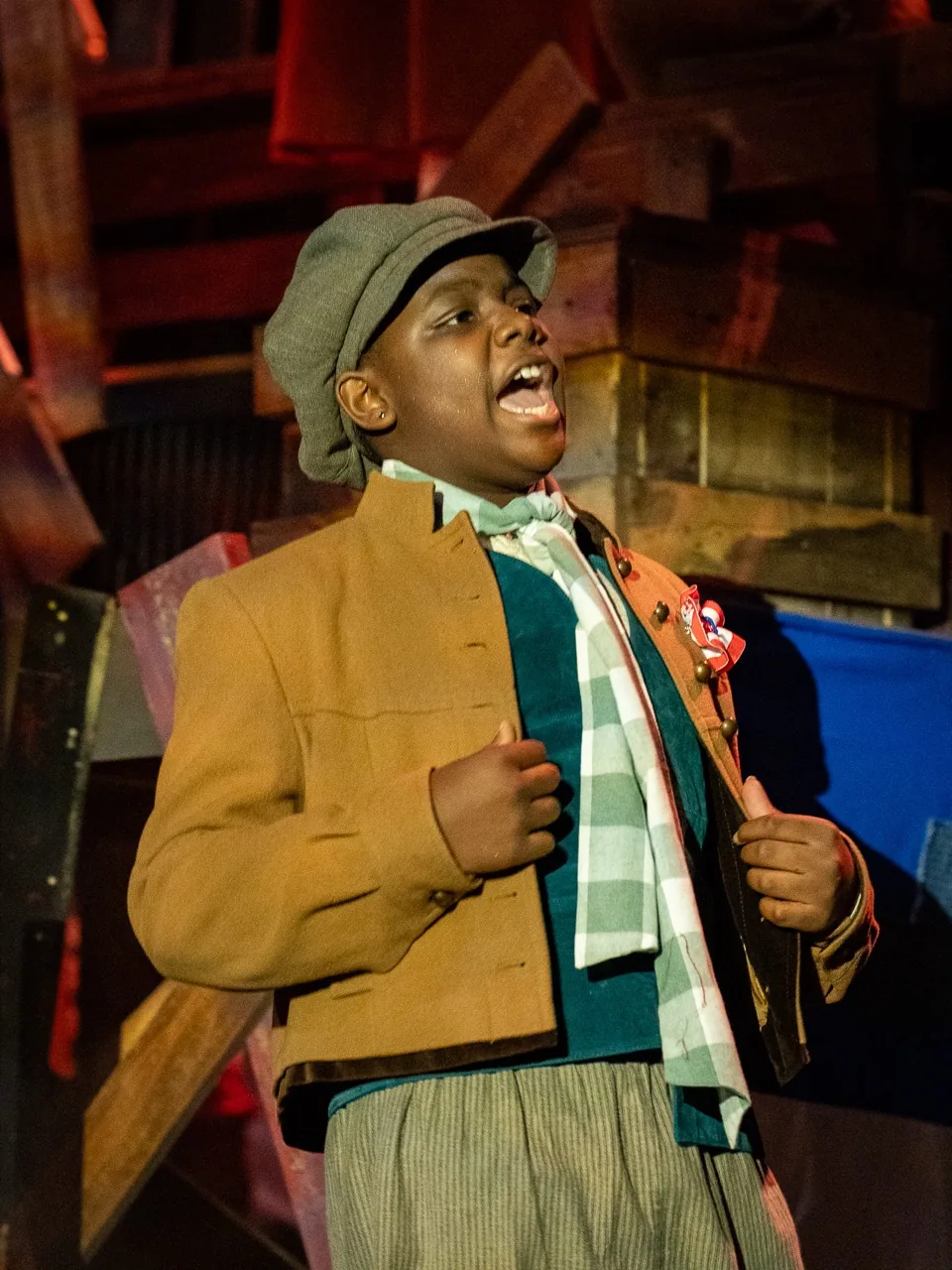 A student performer sings onstage in costume during Les Misérables
