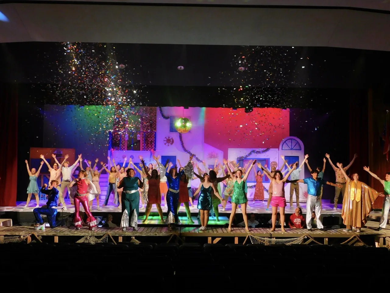 The Mamma Mia company performs together beneath falling confetti